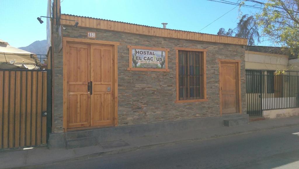 a brick building with wooden doors and a sign on it at Hostal Cactus Copiapo in Copiapó