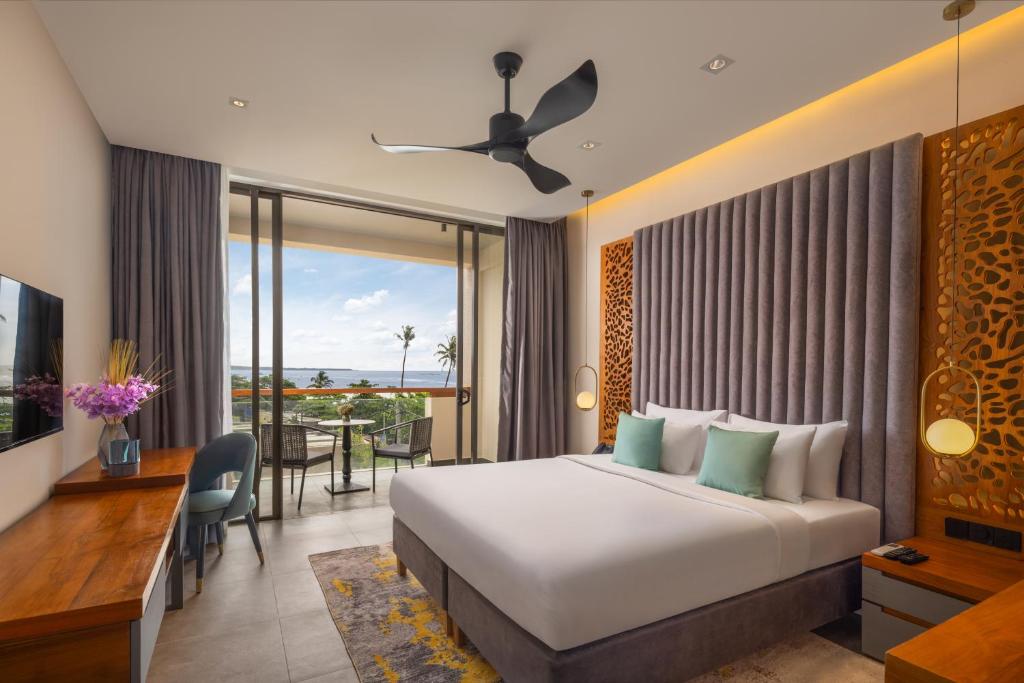 Una habitación de hotel con una cama, un escritorio y un balcón. en Hotel Ferola, en Matara