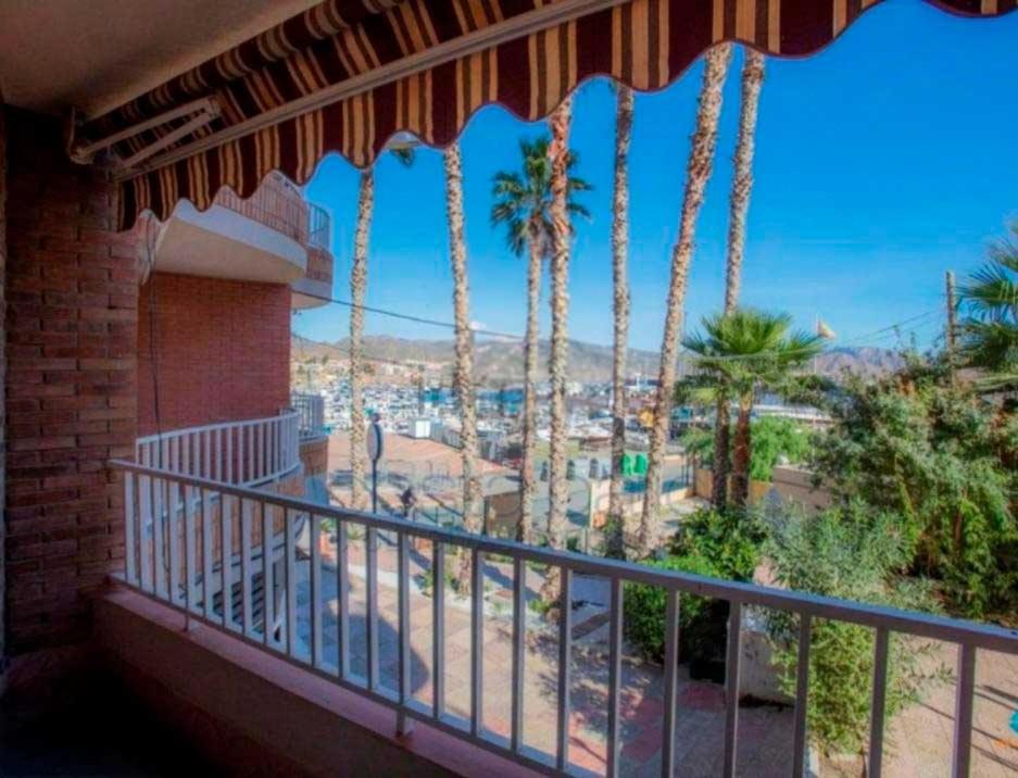 a balcony with palm trees and a view of a city at Adorable Apartamento en la Playa in Puerto de Mazarrón