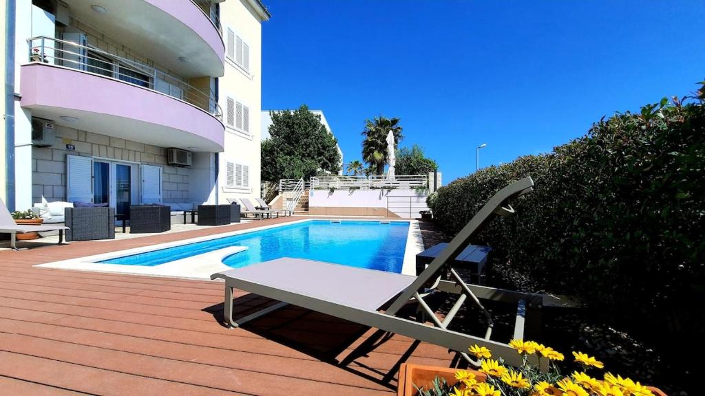 a swimming pool with a bench next to a house at GREEN cozy apartment with shared POOL in Split