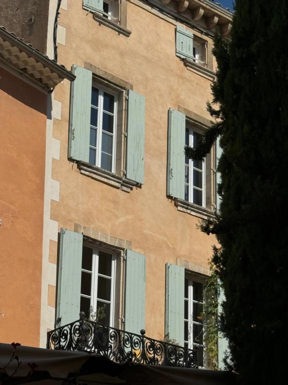 un bâtiment avec des fenêtres vertes à volets dans l'établissement Atlantes de Saint Saturnin, à Saint-Saturnin-lès-Apt