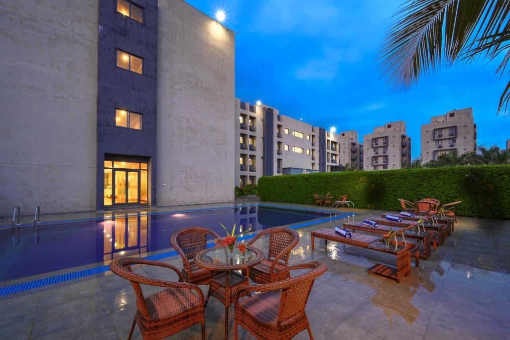 a patio with tables and chairs and a swimming pool at TreeHouse Morina, Vithalapur in Vithalpur