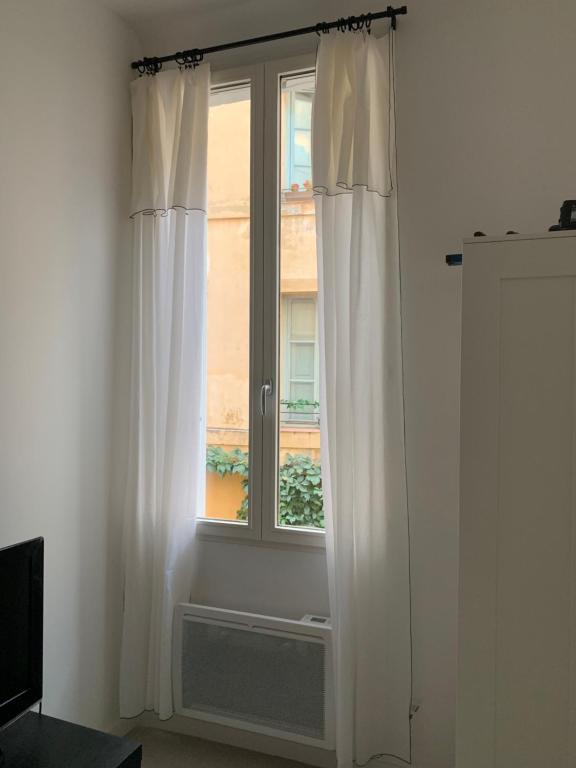 Cette chambre dispose d'une fenêtre avec des rideaux blancs. dans l'établissement Studio au cœur d Aix en Provence, à Aix-en-Provence