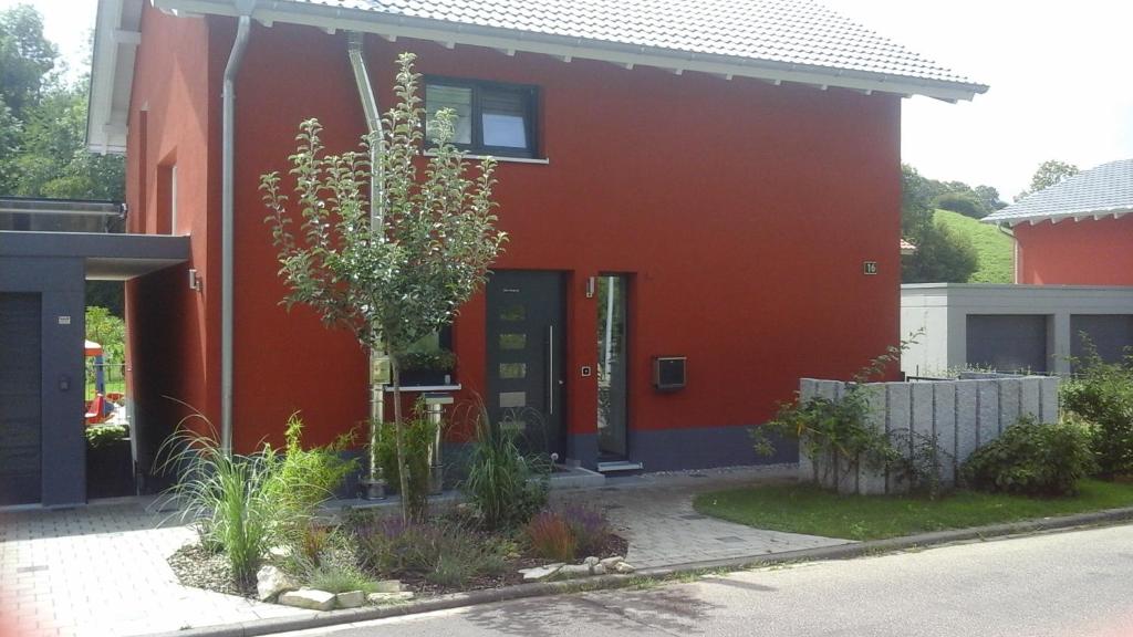 ein rotes Haus mit einem Baum davor in der Unterkunft Ferienwohnung Im Weihergrund in Engen