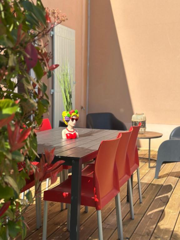 une poupée en jouet assise sur une table en bois avec des chaises dans l'établissement La Maison de Grazou aux Demeures du Ventoux, à Aubignan