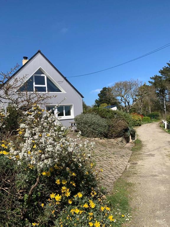 une maison blanche avec des fleurs devant elle dans l'établissement Maison 400m de la plage, à Crozon