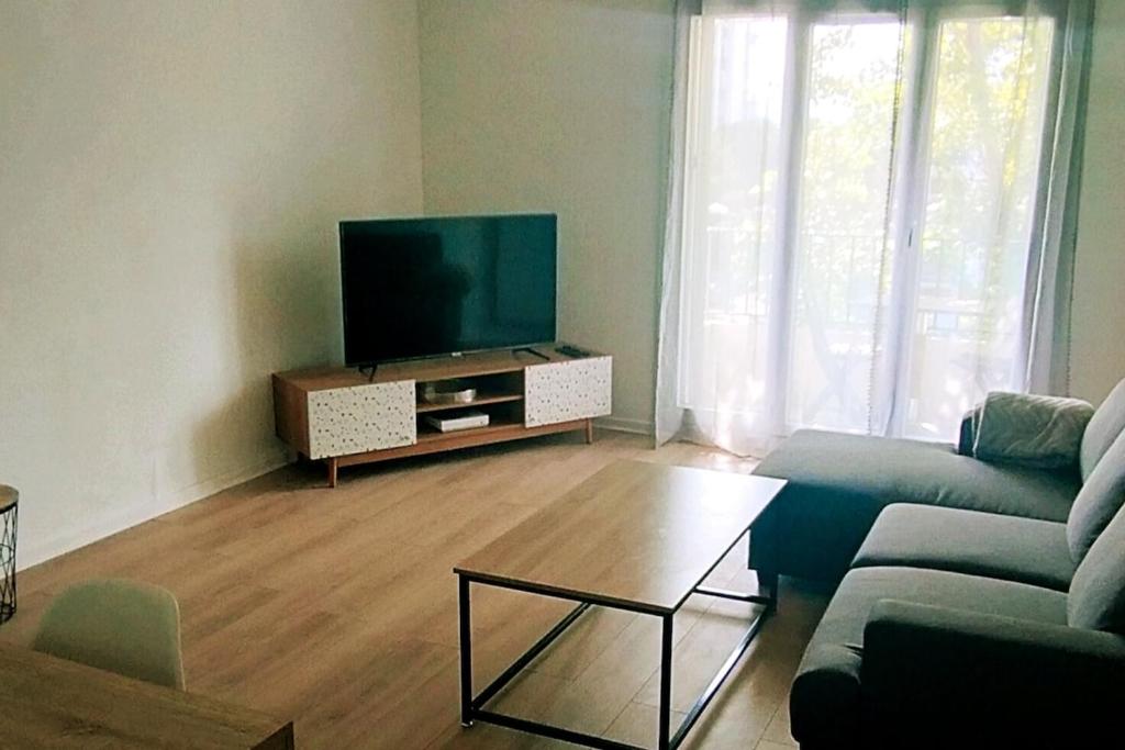 un salon avec une télévision à écran plat et un canapé dans l'établissement Bel appartement Perpignan 15 min de la mer, à Perpignan