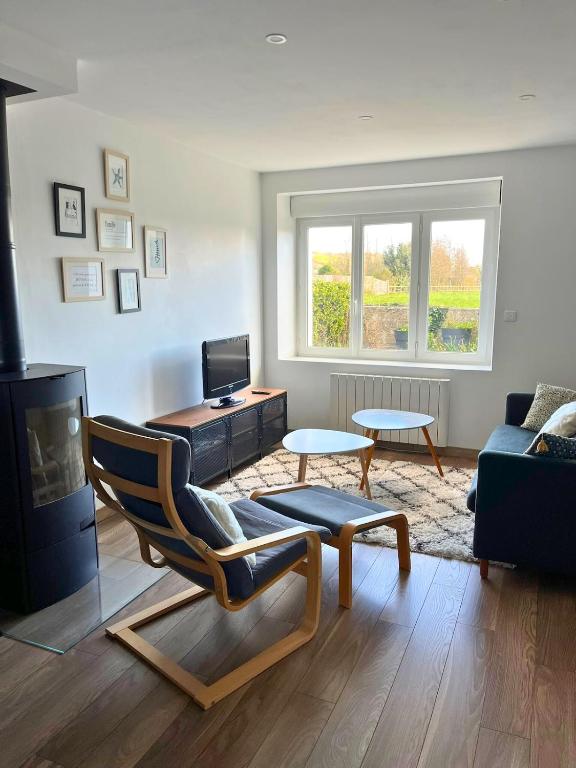 un salon avec une chaise et un canapé dans l'établissement Maison familiale proche de la mer, à Surtainville