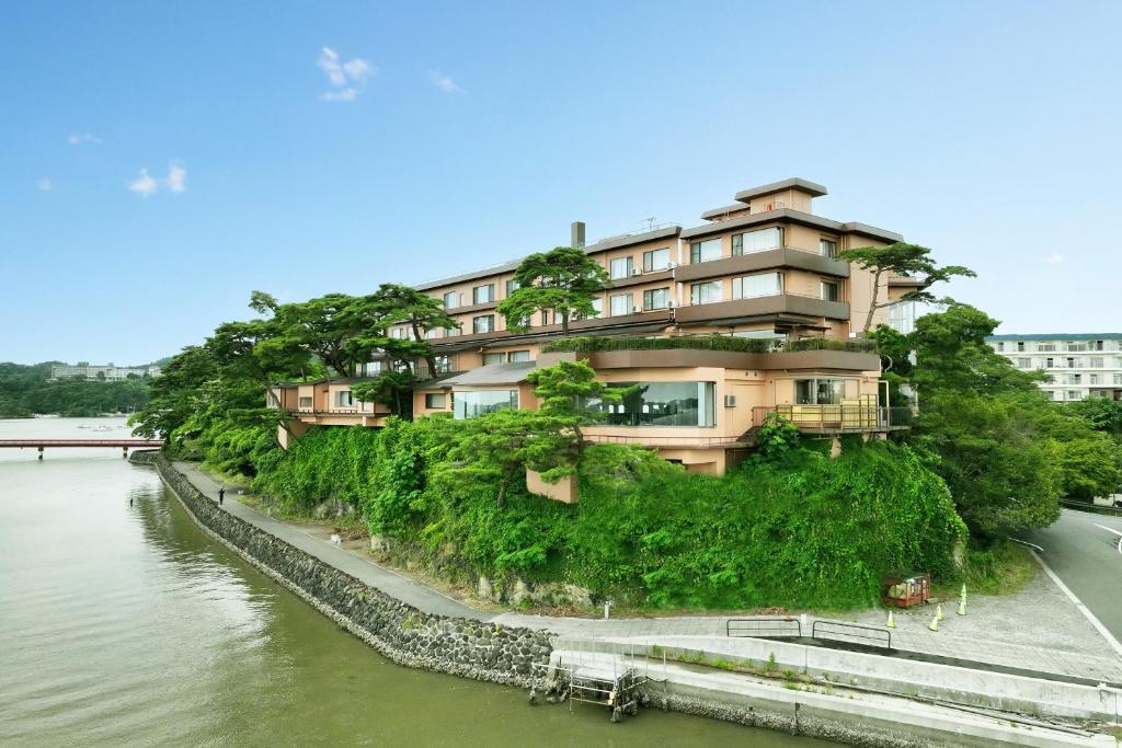 a building on a hill next to a river at Komatsu-kan Kofu-tei in Matsushima