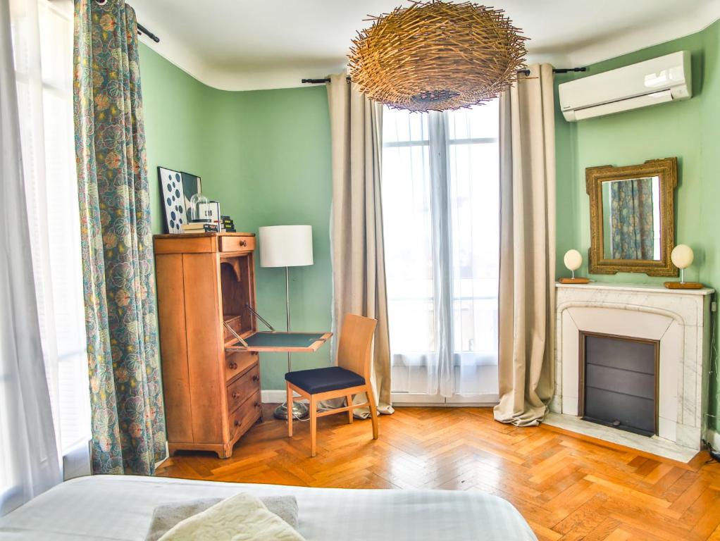 - une chambre avec des murs verts, une cheminée et une chaise dans l'établissement Les Bananiers centre ville Cannes, à Cannes