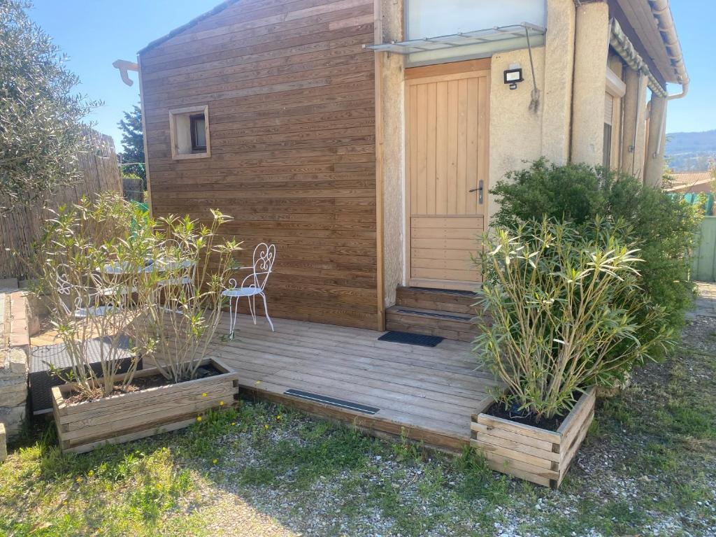 une terrasse couverte en bois avec une chaise sur une maison dans l'établissement La maison Anaïa, à Gargas