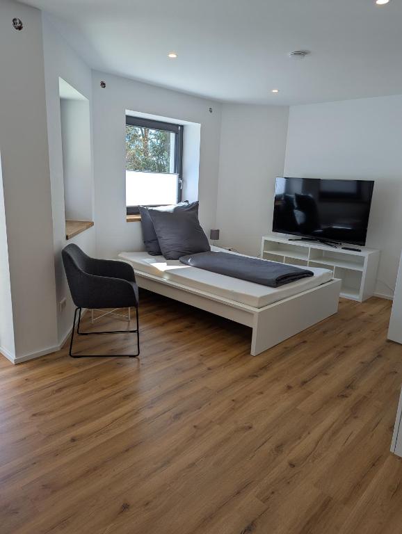 a bedroom with a bed and a tv and a chair at Apartment del Mardy in Ostfildern