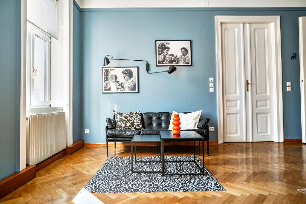 a living room with a black couch and a blue wall at Feel at Home I Bright Windows I Penzing Trainstation in Vienna