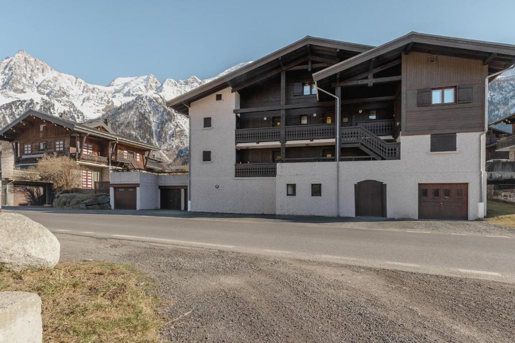 un bâtiment sur le côté d'une route avec des montagnes dans l'établissement Les Arolles - Duplex familial - Vue montagne, aux Houches