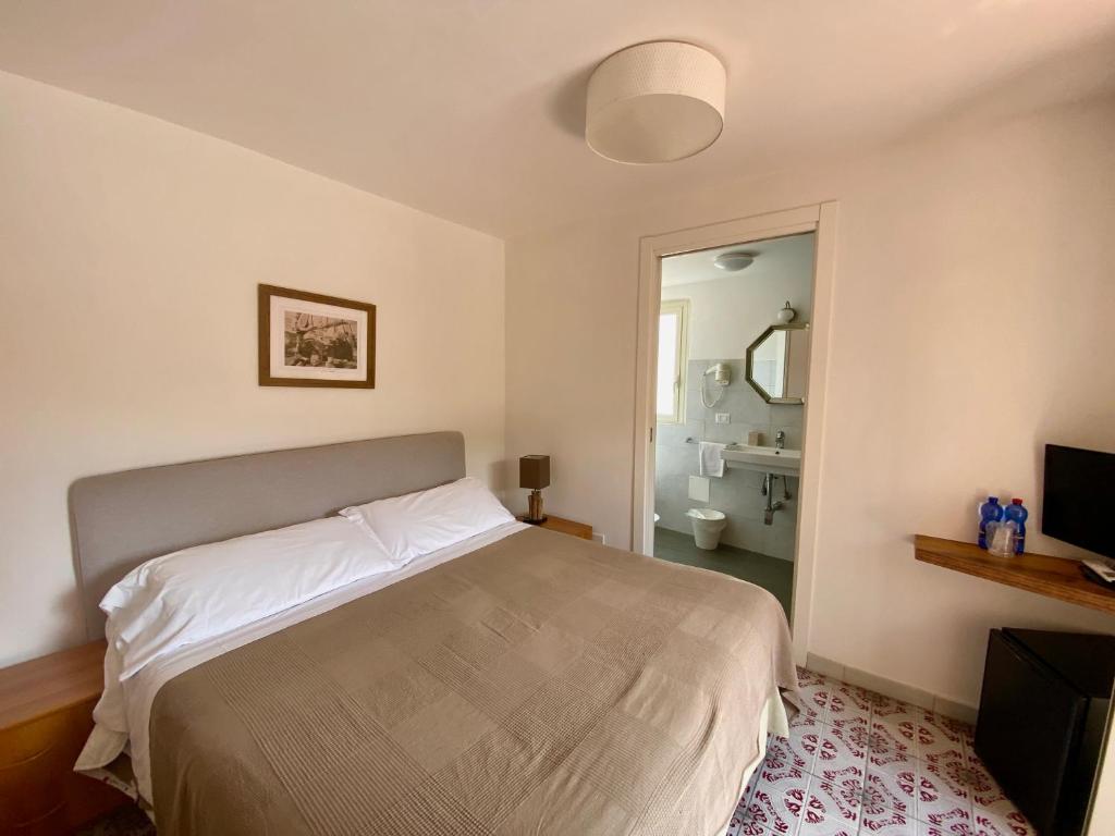 a bedroom with a bed and a bathroom with a mirror at Hotel Villino Gallodoro in Taormina