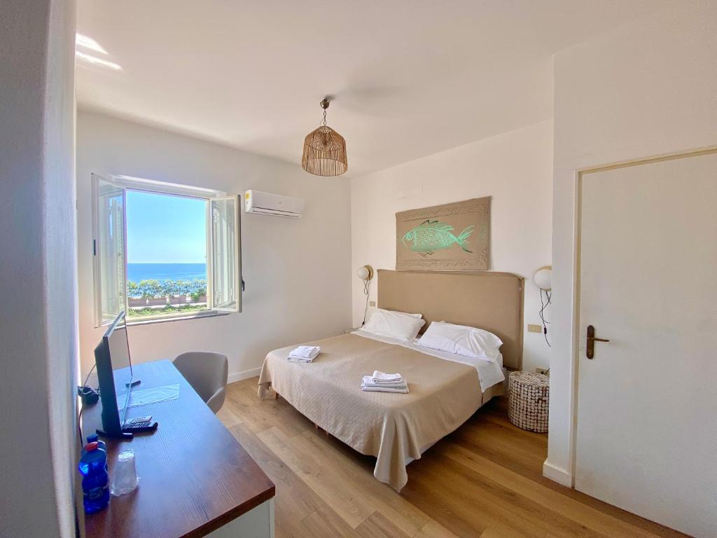 a bedroom with a bed and a desk and a window at Hotel Villino Gallodoro in Taormina