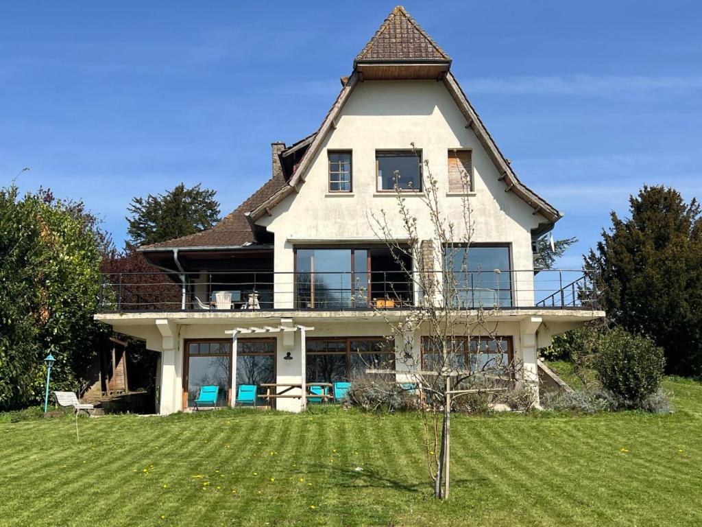 une grande maison avec un toit en gambrel sur une pelouse dans l'établissement Le Jonquet maison 12 pers Sauna Jacuzzi, à Douriez