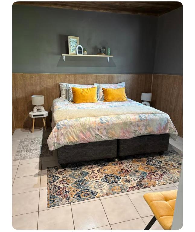 a bedroom with a bed with yellow pillows and a rug at Farm Apartment in Stampriet