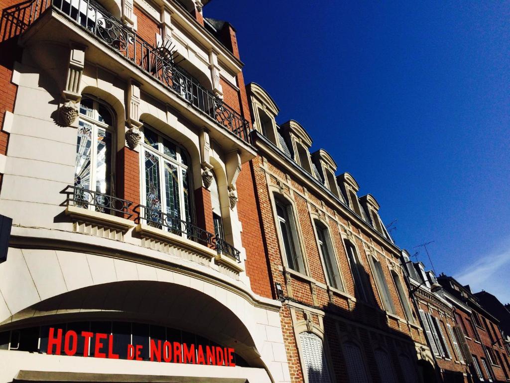 a hotel building with a sign on the side of it at Hôtel De Normandie in Amiens