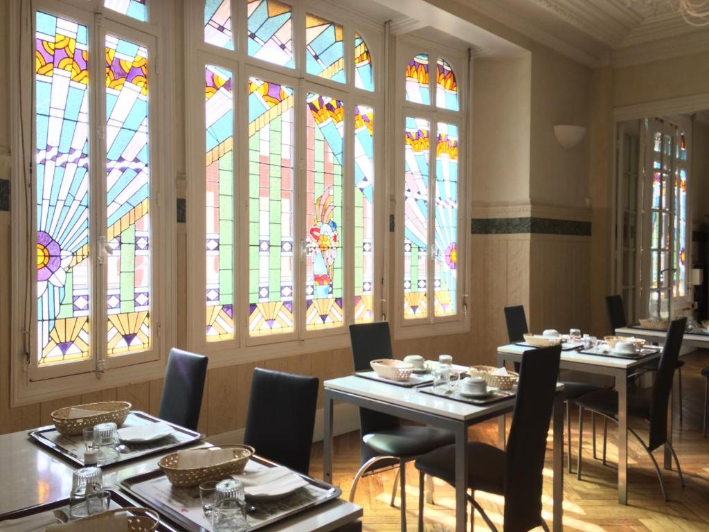 a dining room with two tables and stained glass windows at Hôtel De Normandie in Amiens