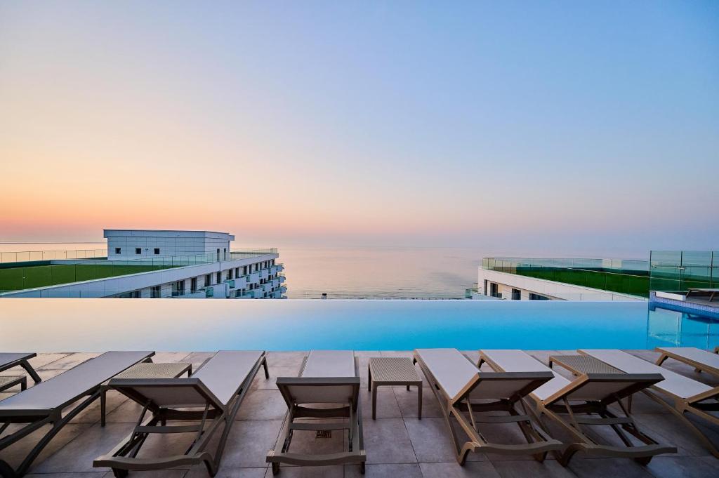 a pool on the roof of a building with chairs at Sea Reflections in Infinity Pool & Spa Resort in Mamaia Sat/Năvodari