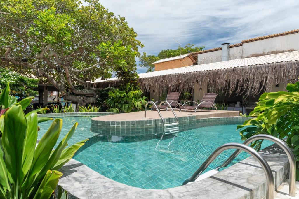 a swimming pool with two chairs in a yard at Pousada Sempre Graciosa in Praia do Frances