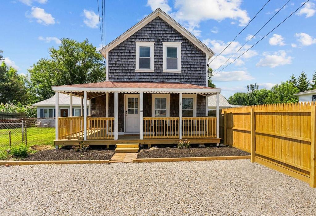 a house with a porch and a wooden fence at Portsmouth Beach cottage in Portsmouth