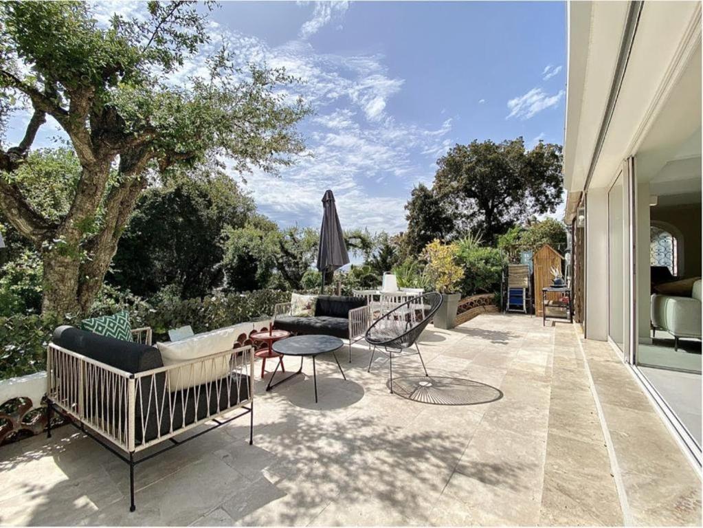 une terrasse avec des chaises, un canapé et un parasol dans l'établissement Lovely 2 bedroom garden apartment in Cannes, à Cannes