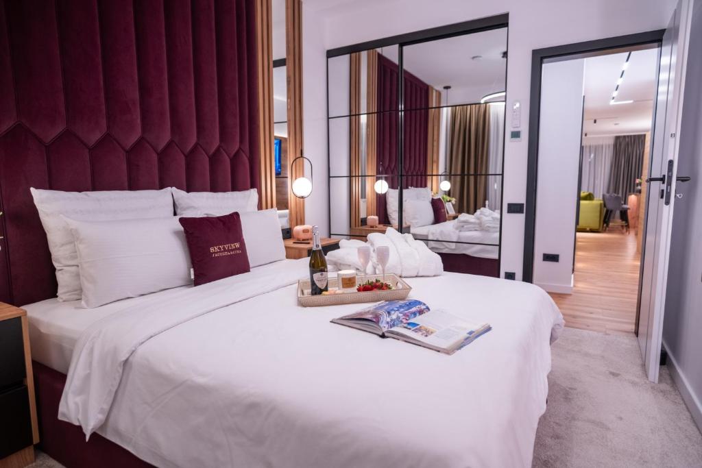 a large white bed with a tray of food on it at Jacuzzi & Sauna Skyview in Cluj-Napoca