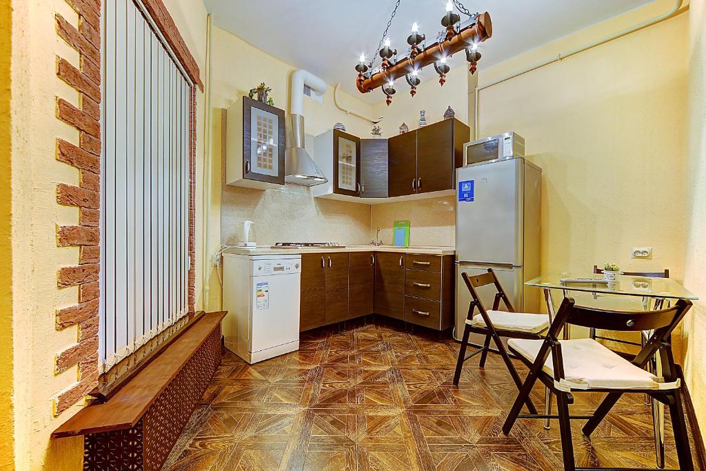 een keuken met een tafel en stoelen en een koelkast bij Shyval Apartment Vosstaniya 35 in Sint-Petersburg