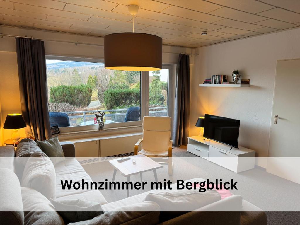 un salon avec un canapé, une télévision et une fenêtre dans l'établissement FeWo Berg-Domizil Altenau inklusive Bettwäsche und Handtüchern, à Altenau