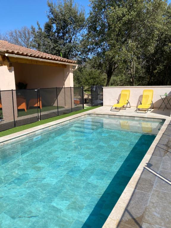 une piscine avec deux chaises jaunes et une maison dans l'établissement Maison de campagne avec piscine à Bédoin, Mont Ventoux, à Bédoin
