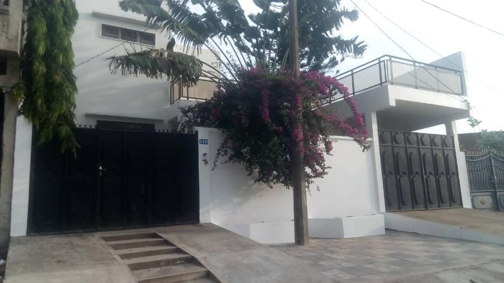 une maison avec une porte noire et des fleurs sur elle dans l'établissement Villa Fidjrossè, Cotonou, à Cotonou