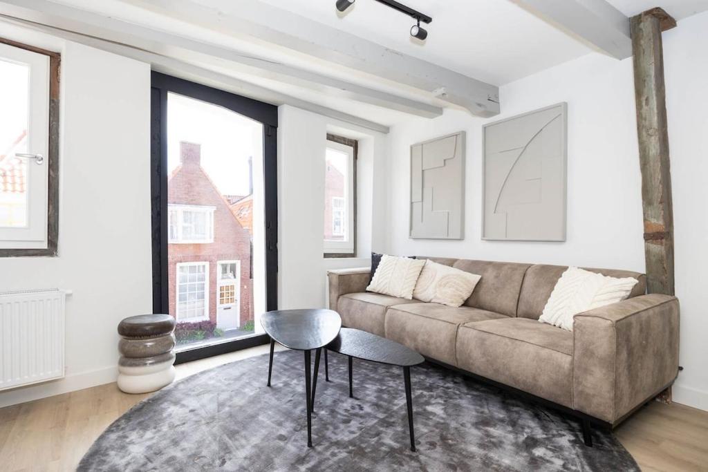 Una sala de estar con un sofá y algunas ventanas. en Apartment Hoorn Center Original - extended stays by Haring Verhuur, en Hoorn