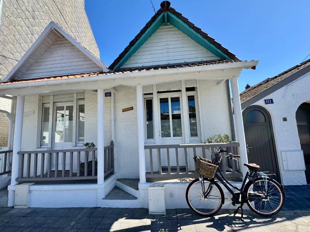 a bike parked in front of a white house at Petite maison de charme in Le Touquet-Paris-Plage