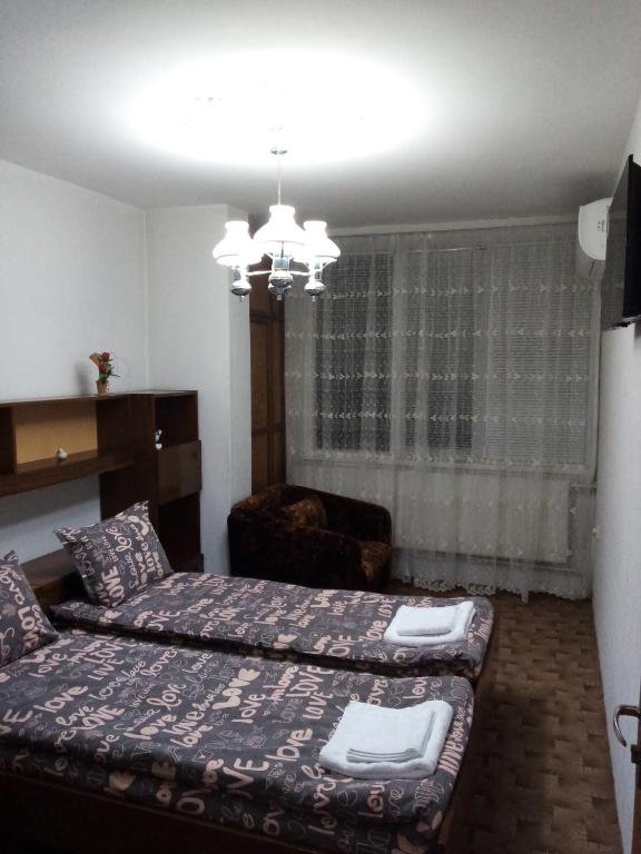 a bedroom with two beds and a chair in it at Апартамент Димови in Tryavna