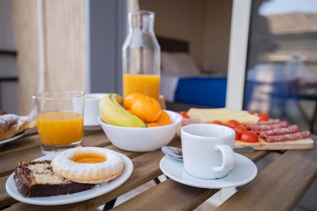 una mesa de madera con productos para el desayuno y un vaso de zumo de naranja en My Home Catania Rooms, en Catania