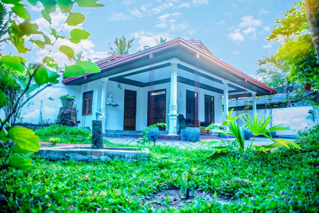 a white house with a red roof at Tropical Dream Villa Habarana in Moragaswewa