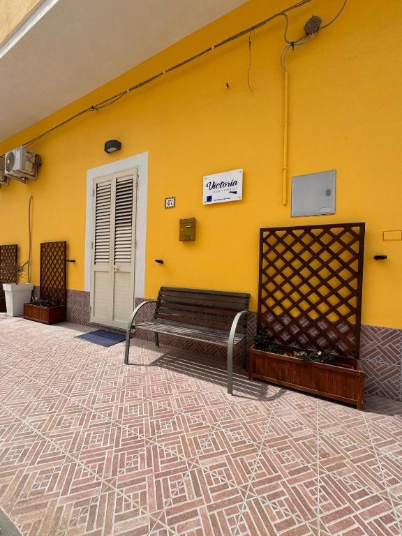 a yellow wall with a bench in front of it at Victoria apartments in Lampedusa