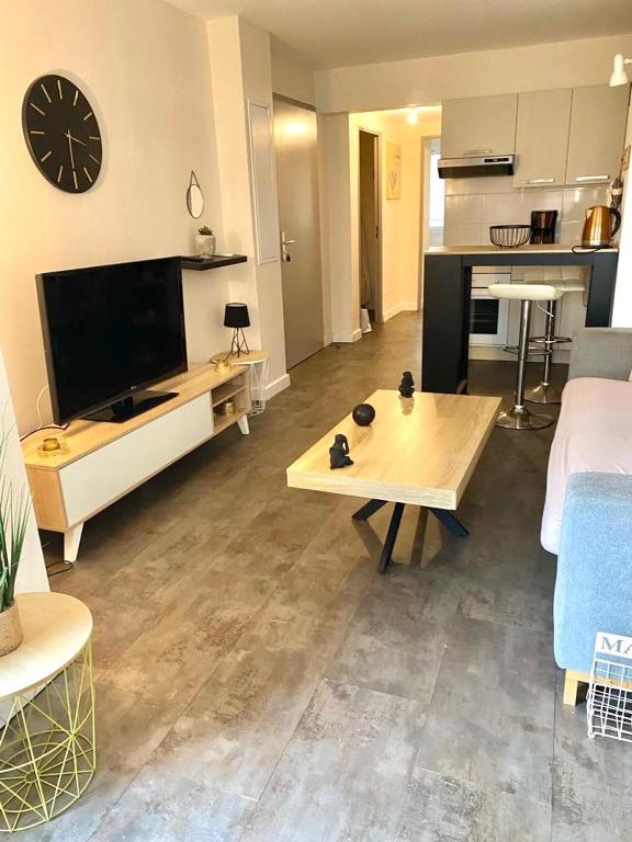 un salon avec une grande télévision et une table dans l'établissement Appartement cosy au cœur de port vendres, à Port-Vendres