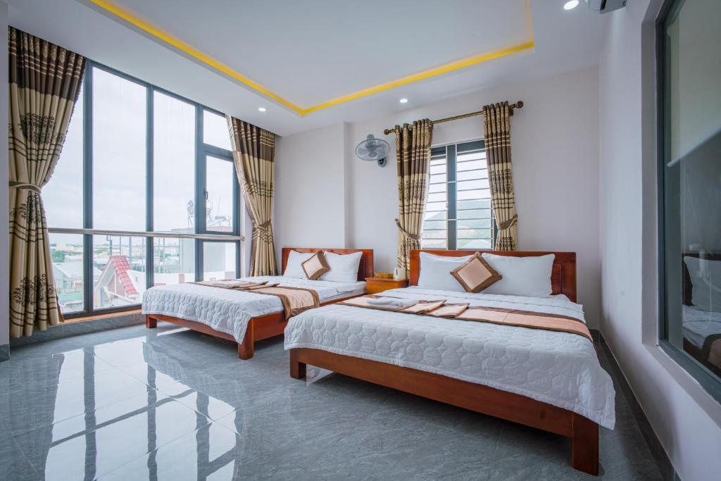 two beds in a room with large windows at P Xuân Quy Nhơn Hotel in Quy Nhon