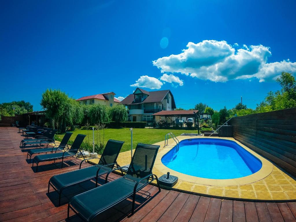 a group of chairs sitting next to a swimming pool at Pensiunea Regina Deltei in Băltenii de Sus