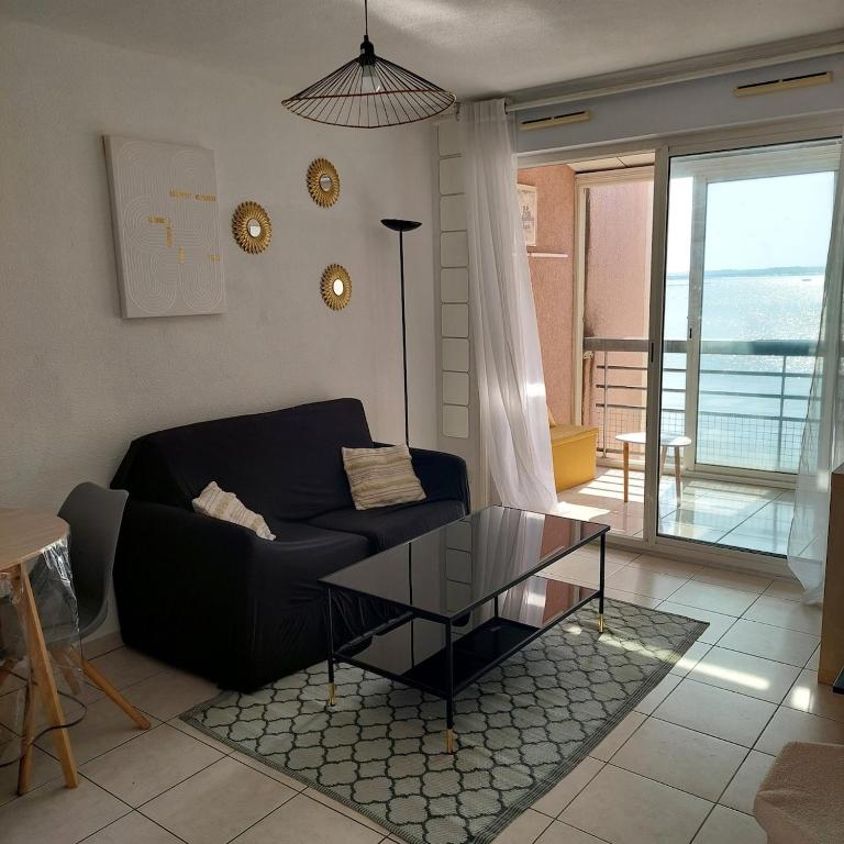 - un salon avec un canapé noir et une table en verre dans l'établissement T3 au bord de l'étang de Thau, à Balaruc-les-Bains