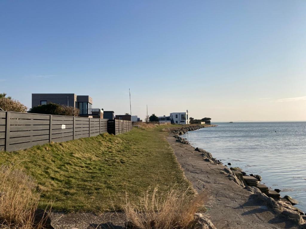 a beach with a fence and the water at Strandhuus Westerbergen - direkt am Meer bei Lemkenhafen in Fehmarn