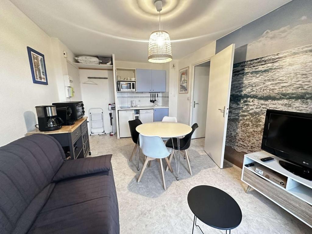 un salon avec un canapé et une table et une cuisine dans l'établissement horizon détente, 2 pas de la mer, à Ouistreham