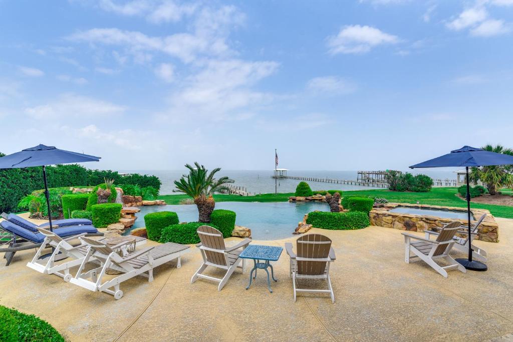 a patio with chairs and umbrellas next to a pool at Private Dock and Pier Luxe Villa on Galveston Bay! in San Leon