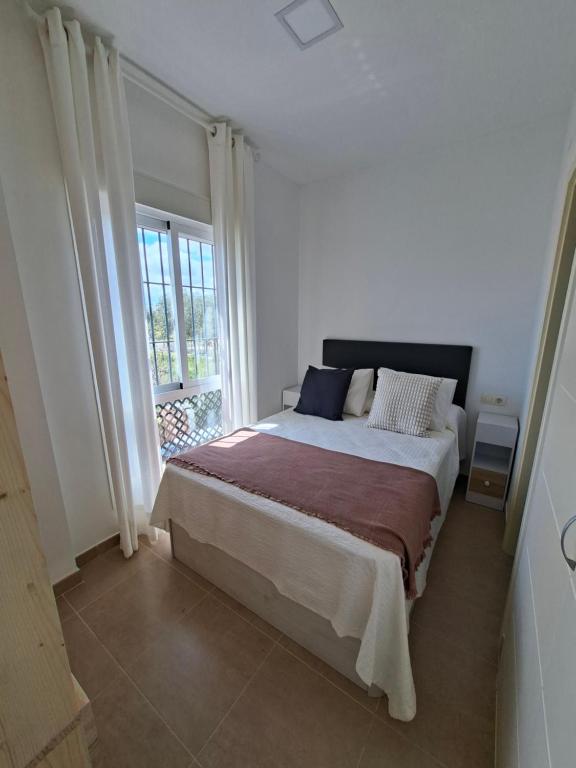 a bedroom with a large bed and a window at Apartamento con piscina Bormujos in Bormujos