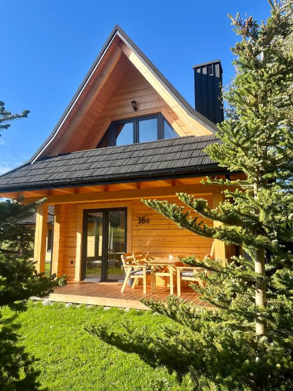a log cabin with a wooden deck and a table at Miło Zakopane in Zakopane