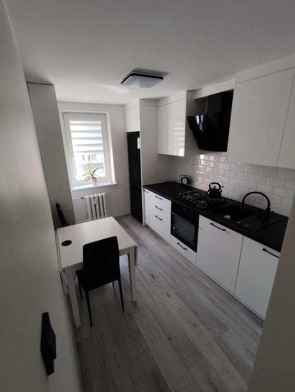 a kitchen with white cabinets and a table and a window at Sweet Apartament 6 osobowy in Płock