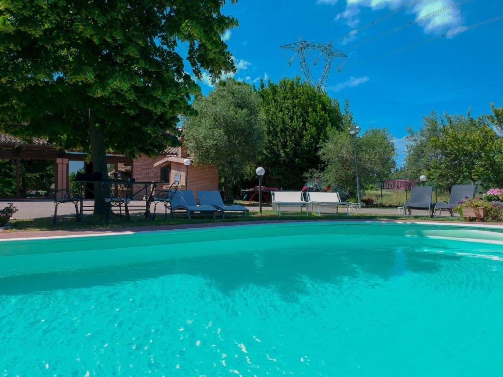 einen großen Pool mit blauen Stühlen und Bäumen in der Unterkunft Villa Ferrara Royal Resort & Spa in Coriano